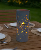 Decorative lantern with butterfly design on a wooden table outdoors