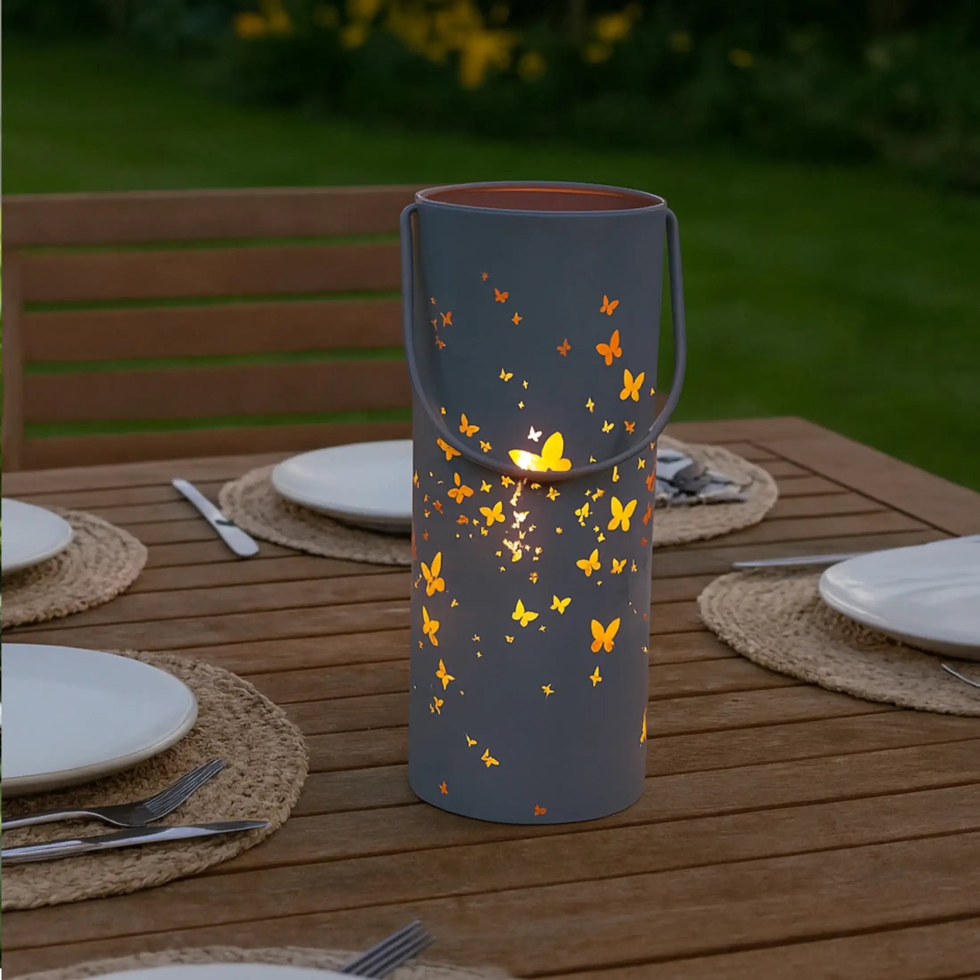 Decorative lantern with butterfly design on a wooden table outdoors