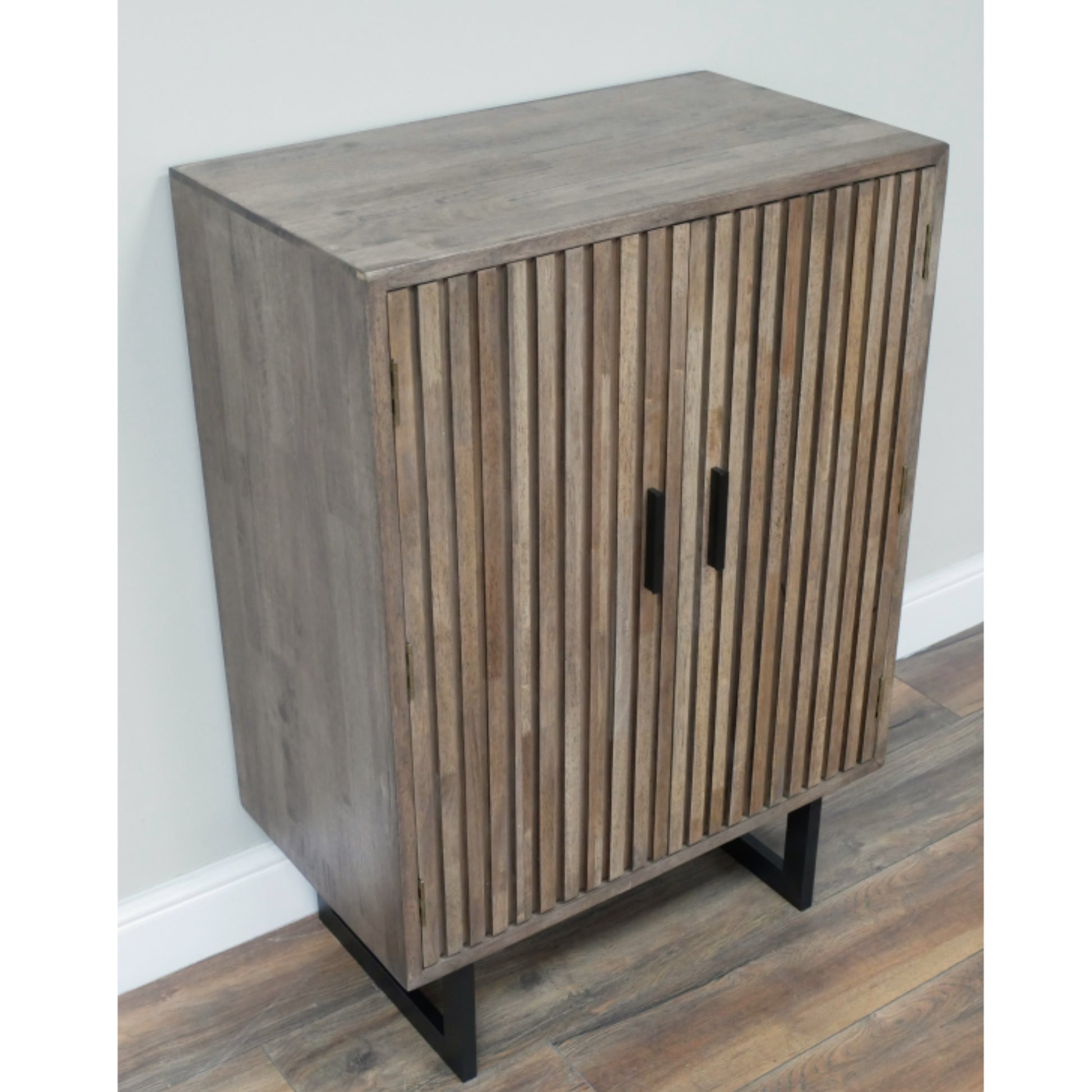 Wooden cabinet with slatted design on a wooden floor against a white wall