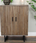 Wooden cabinet with slatted design on a wooden floor with decorative plants.
