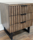 Wooden side table with three drawers on a wooden floor.