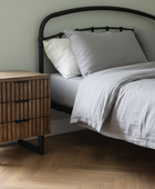 Bedroom with a bed and wooden nightstand.