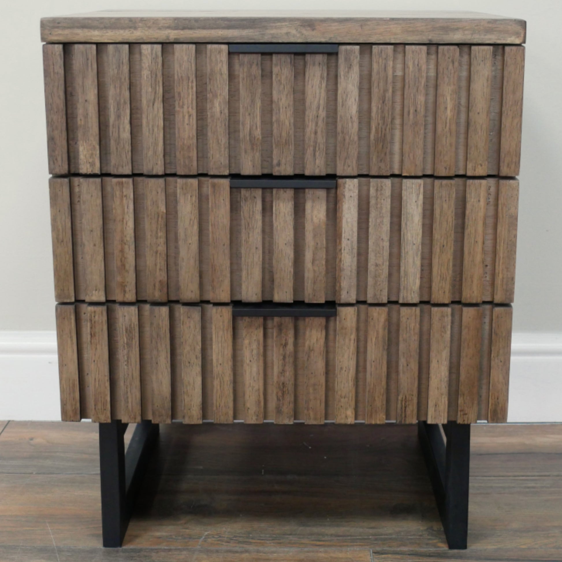 Wooden side table with a striped pattern and black legs on a wooden floor.