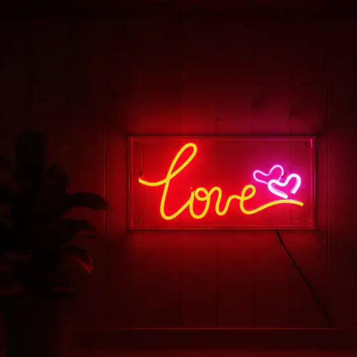Neon sign with 'love' and heart symbol on a dark background
