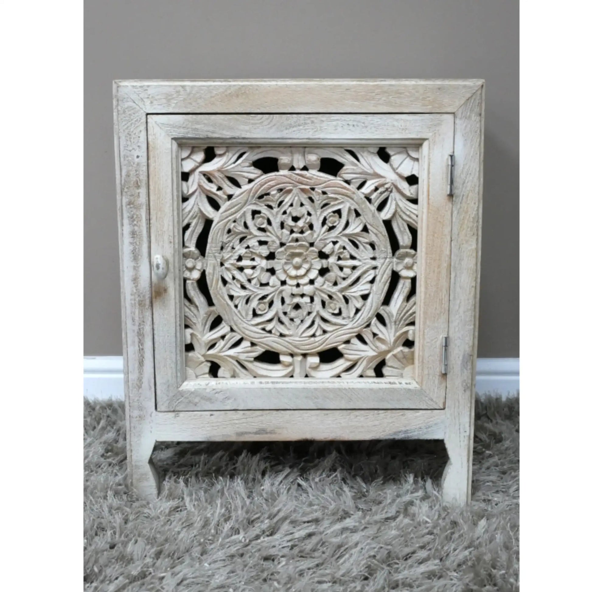 Carved wooden cabinet with intricate patterns on a gray surface