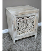 Wooden side table with intricate carvings on a gray carpet