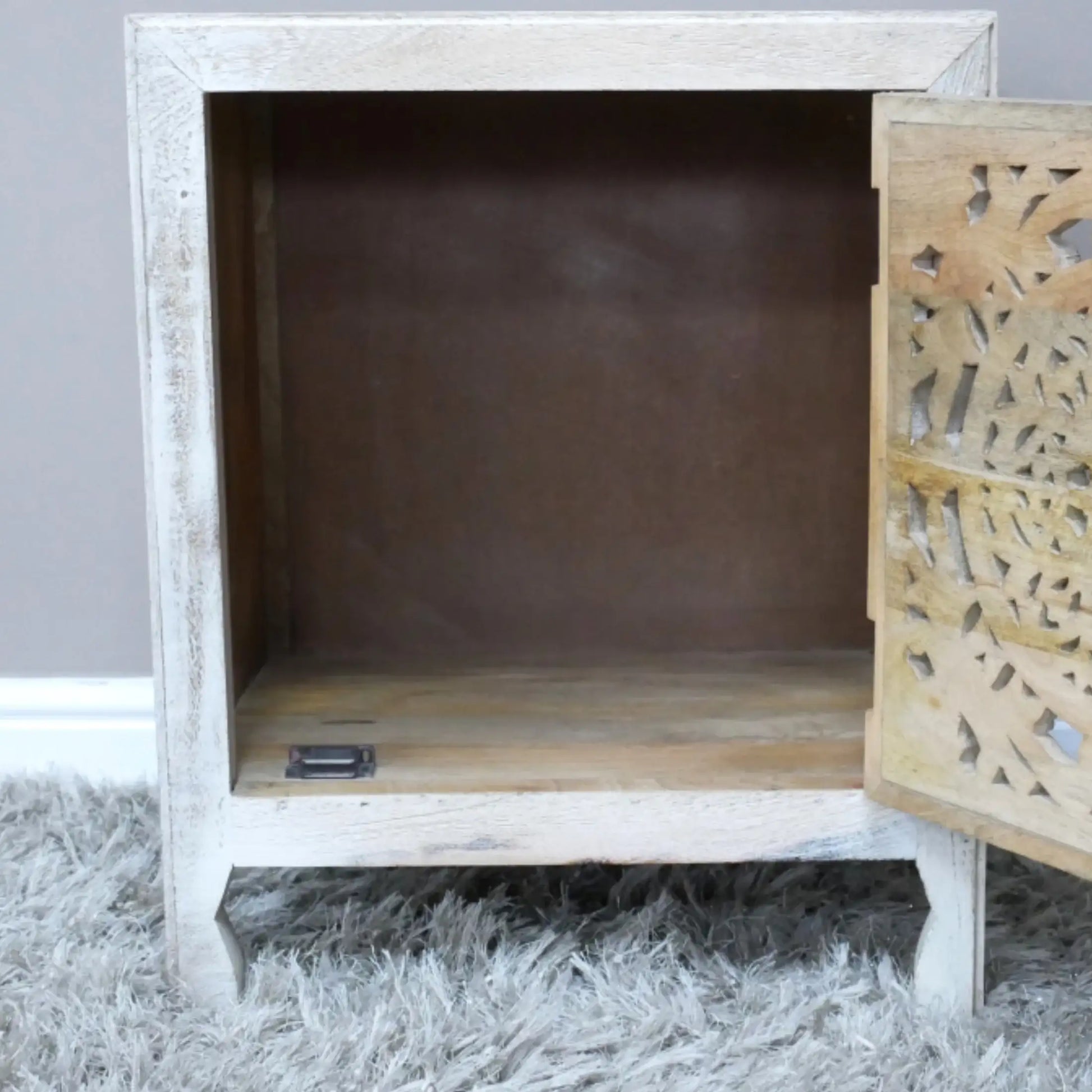 Wooden cabinet with intricate carvings on a gray surface