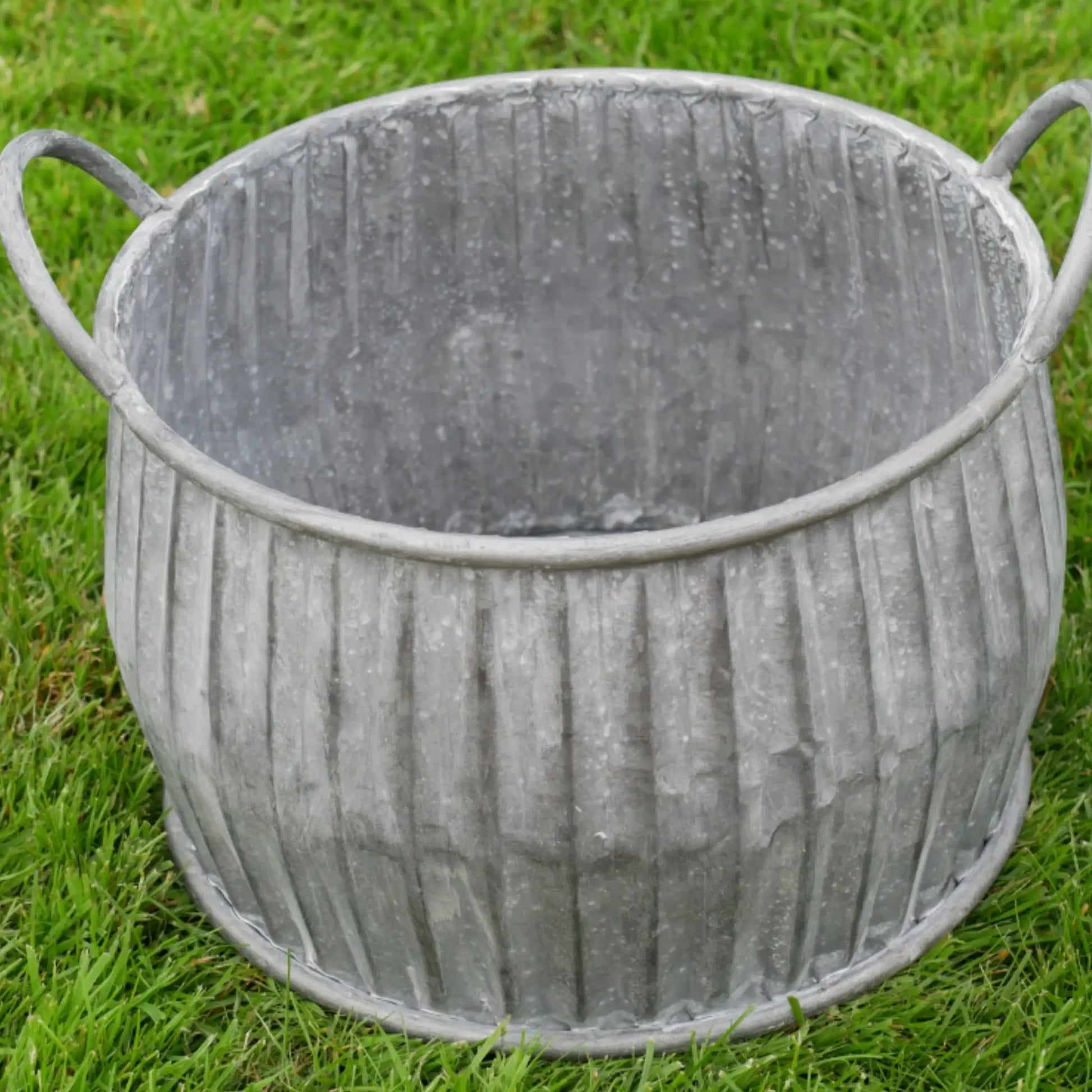 Metal planter with ribbed texture on a grass background