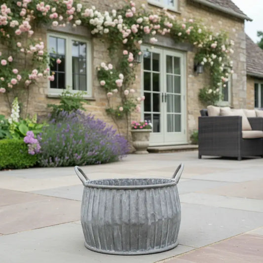 Decorative outdoor setting with a stone building, flowers, and a gray planter.