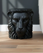 Black lion head sculpture on a wooden floor with a dark wall background