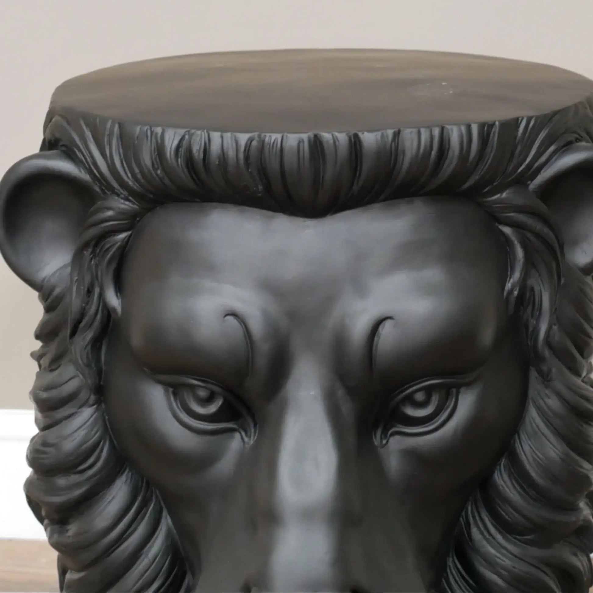 Black lion head stool with a neutral background