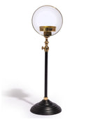 A vintage-style table lamp featuring a large, clear glass globe shade on a black metal stand with polished brass accents and a tiered circular base, set against a plain white background.