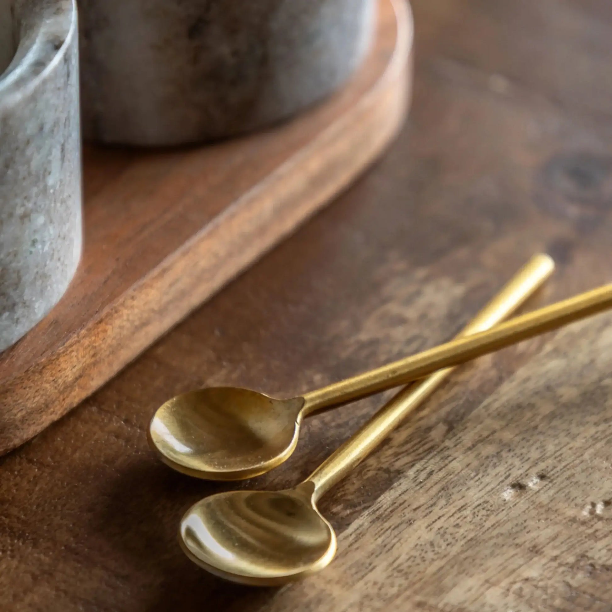 Two gold spoons on a wooden surface with a rustic background