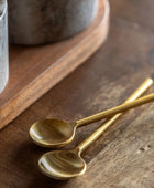 Two gold spoons on a wooden surface with a rustic background