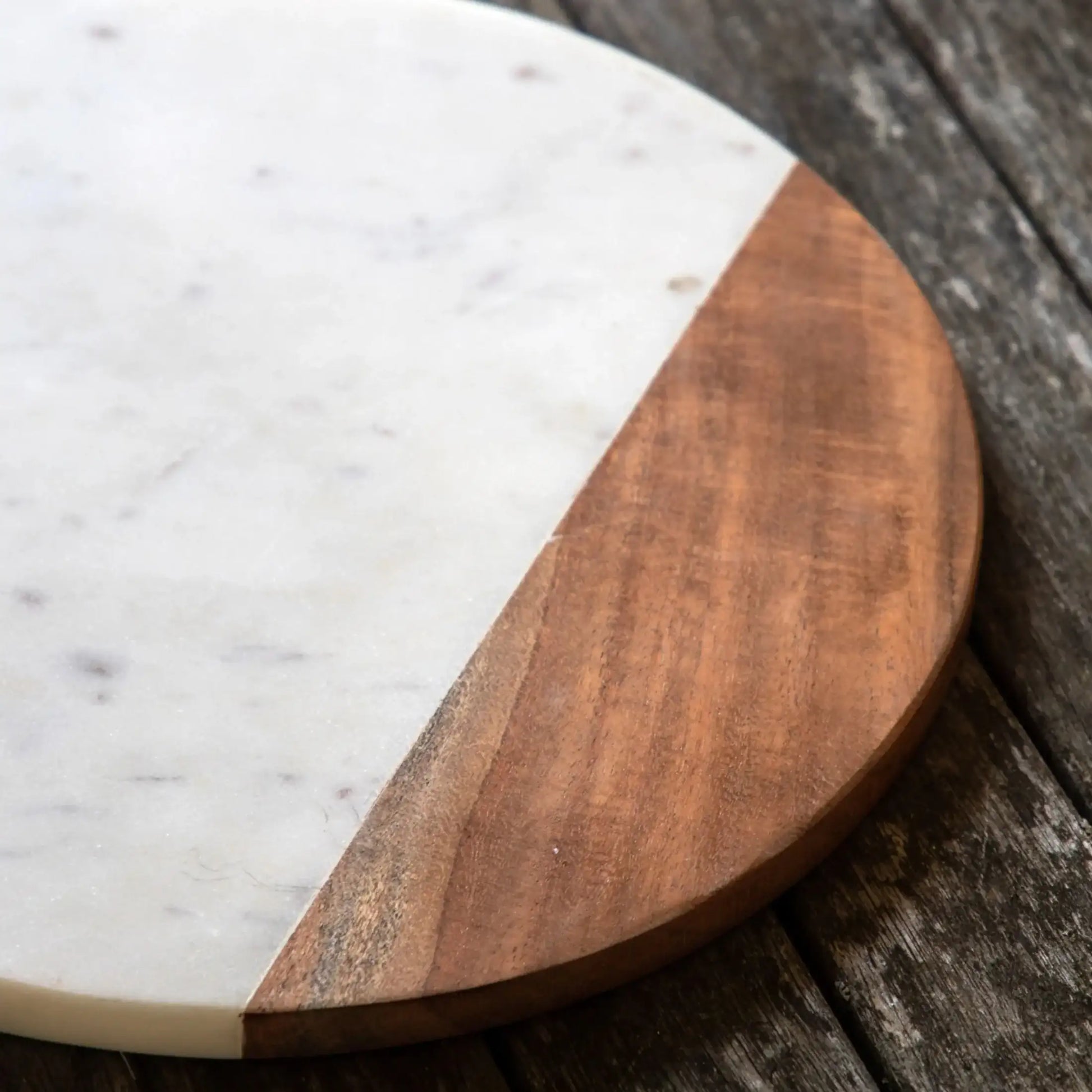 Round wooden and marble cutting board on a rustic wooden surface
