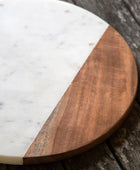 Round wooden and marble cutting board on a rustic wooden surface