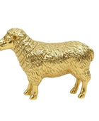 A polished gold-colored metal figurine of a sheep, showcasing detailed textured wool and a shiny, reflective finish, set against a plain white background.