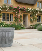 Decorative planter in front of a house with floral arrangements.