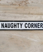 Decorative sign with 'NAUGHTY CORNER' text on a wooden surface