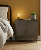 Bedroom with a wooden nightstand, lamp, and plant against a yellow wall.