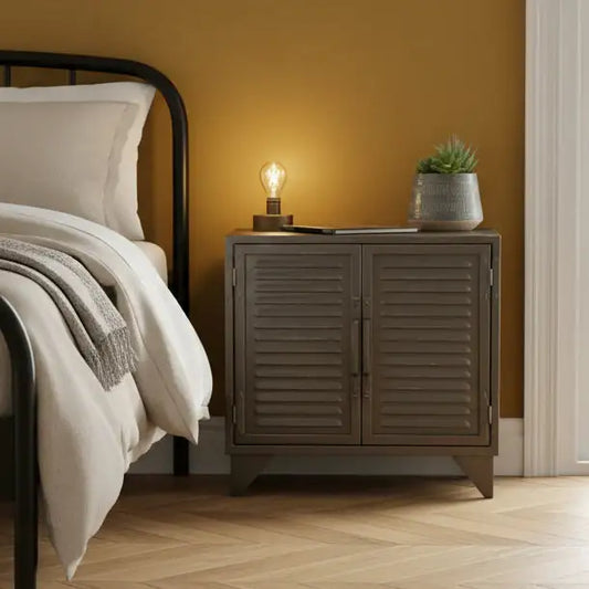 Bedroom with a wooden nightstand, lamp, and plant against a yellow wall.