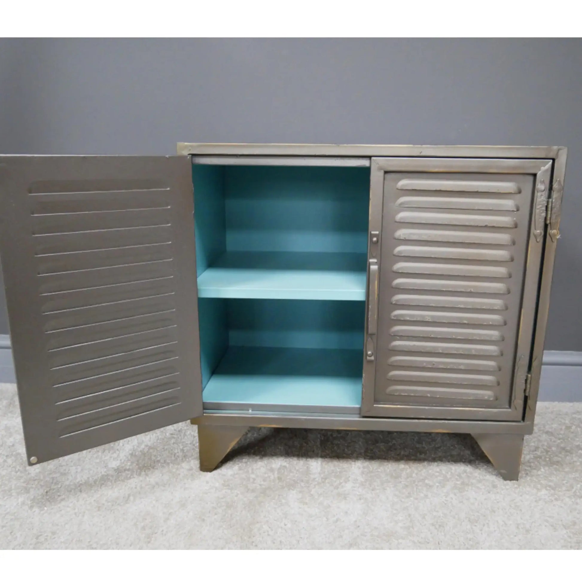 Metal cabinet with open doors revealing a turquoise interior against a gray wall.
