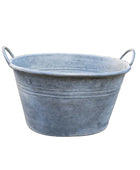 Galvanized metal tub on a stone patio with garden background