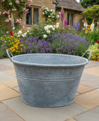 Metal basin on a stone patio with a garden in the background