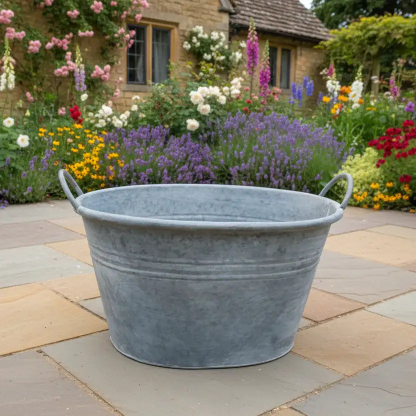 Metal basin on a stone patio with a garden in the background