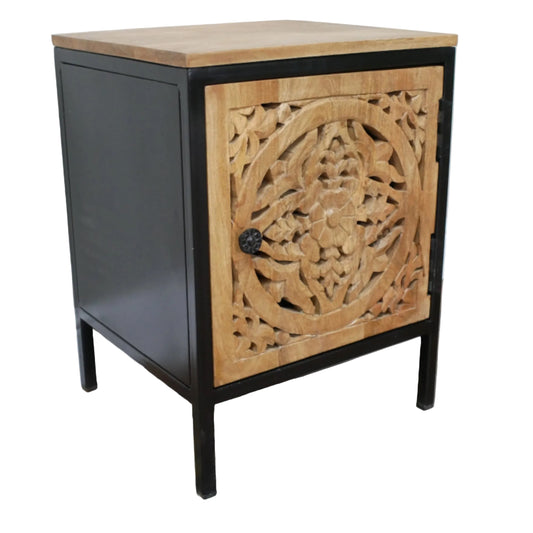 Small cabinet with wooden top and intricate carvings on a black frame against a white wall.