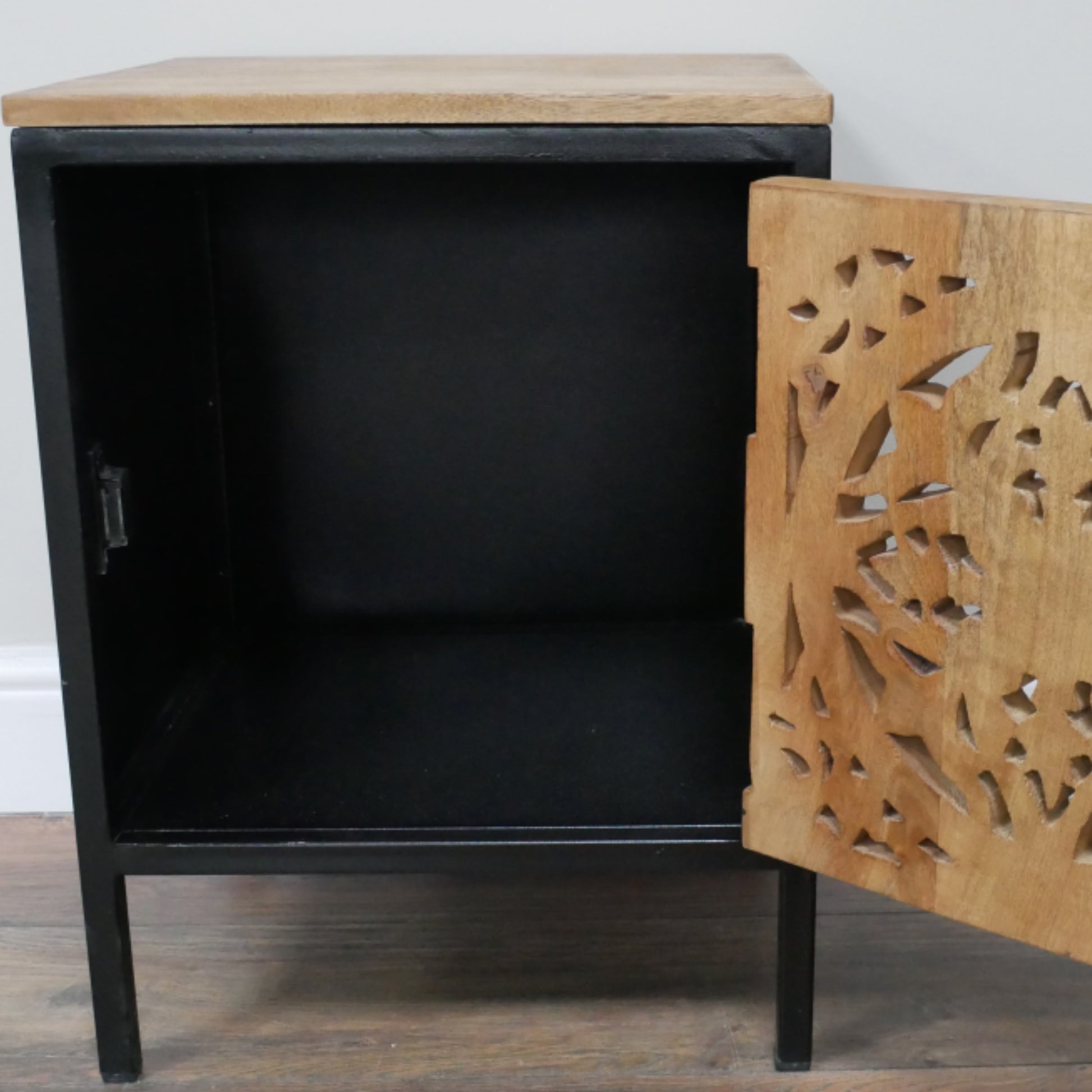Black cabinet with a wooden top and decorative wooden side panel on a wooden floor.