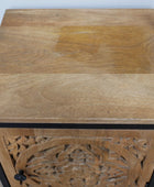 Wooden side table with intricate carvings on a plain background