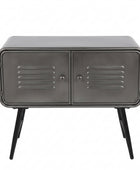 A rustic industrial sideboard cabinet with a galvanized steel finish, featuring two doors with horizontal vent slats, angled metal legs, and decorative items on top, set against a brick wall and wooden floor.