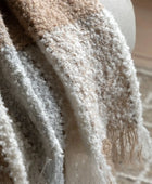 Close-up of a textured beige and brown blanket with a blurred background