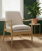 Beige armchair with wooden frame in a room with green walls and a patterned rug.