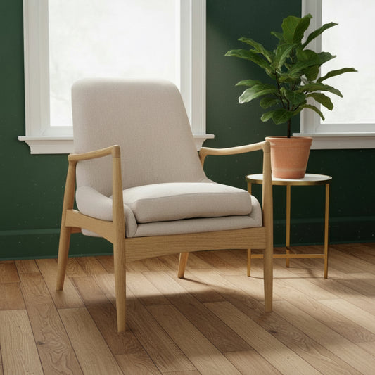 Beige armchair with wooden frame in a room with green walls and a patterned rug.