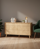 Wooden dresser with decorative items in a room with a green chair and plant.