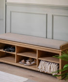 Wooden bench with cushion and storage compartments against a paneled wall.