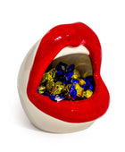 Lip-shaped container with colorful candies inside on a white background