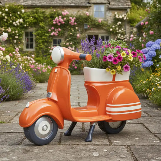 Orange scooter-shaped planter with flowers in a garden setting