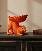 Orange squirrel sculpture with a bowl on a wooden surface