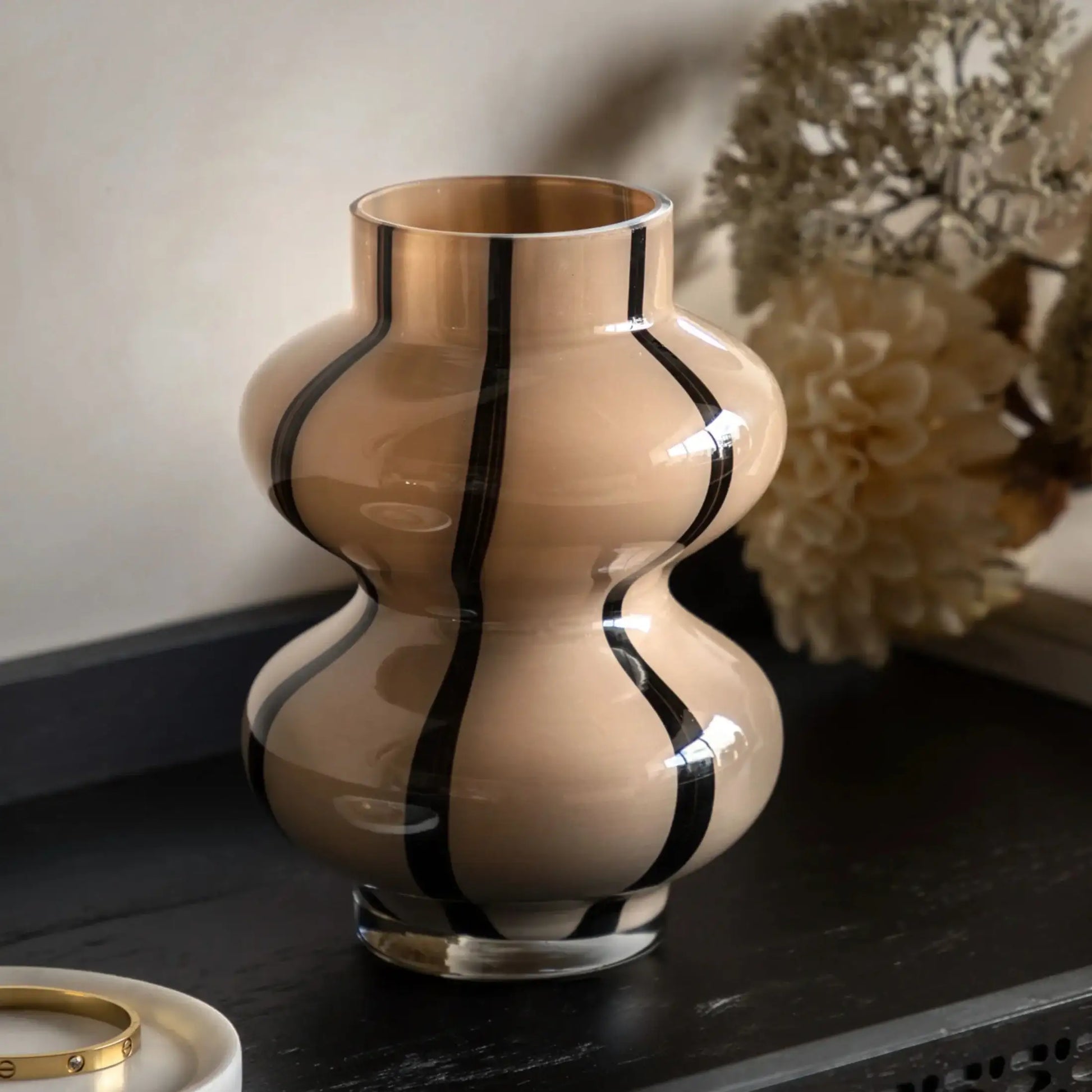 Decorative vase with black stripes on a dark surface