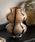 Decorative vase with black stripes on a dark surface