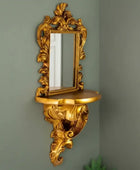 Decorative gold wall mirror with shelf against a green wall