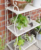 White metal plant stand with plants against a brick wall