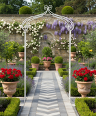 Garden scene with a white archway, potted plants, and a path leading to a stone wall.