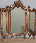 Ornate gold mirror set on a plain background