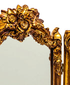 Decorative gold mirror with intricate floral designs on a white background