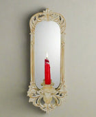 Decorative wall mirror with a candle holder on a white background