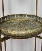 Decorative metal tray on a stand with intricate patterns against a plain background